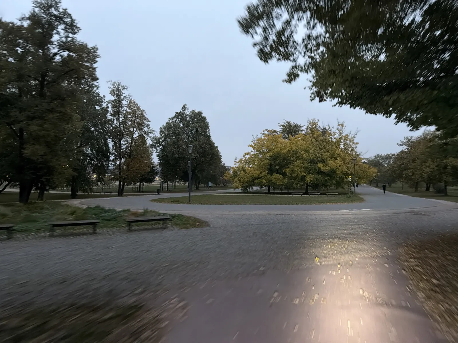 Rozcestí parkových cest na Letné, mezi lavičkami a podzimními stromy.