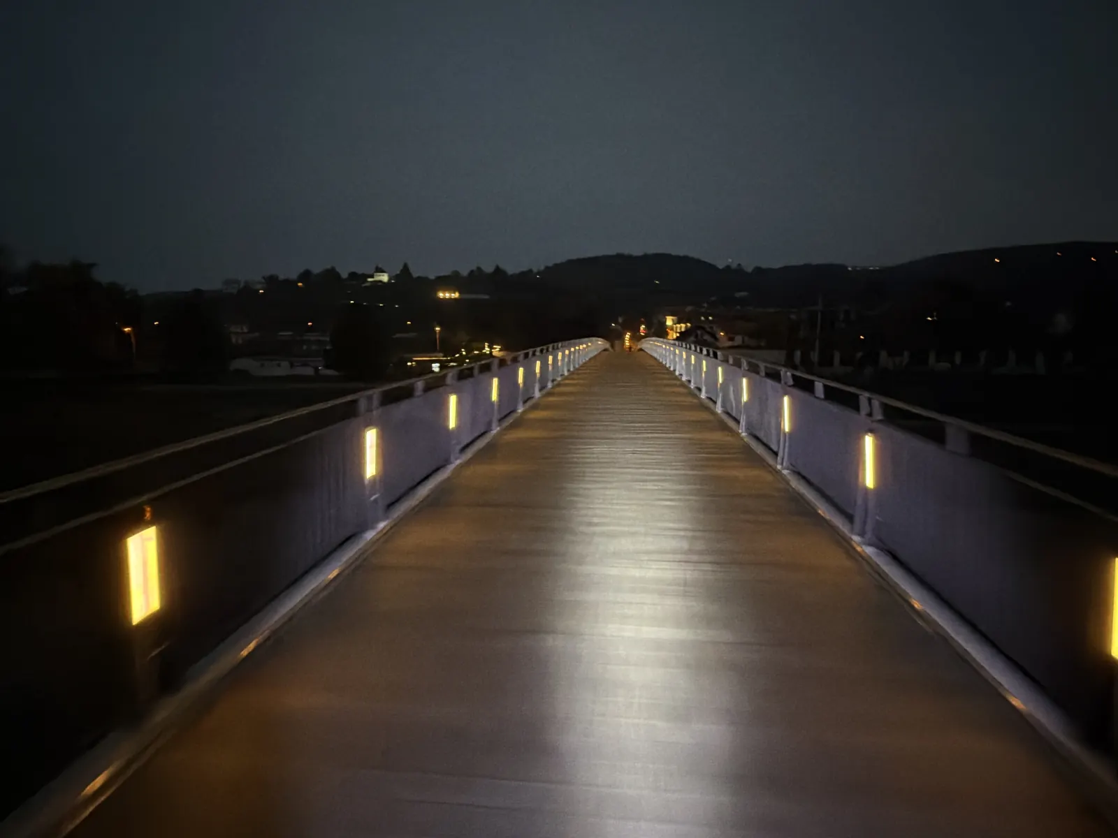Přejezd Trojské lávky, cestu osvětlují světla v zábradlí a přední reflektor.